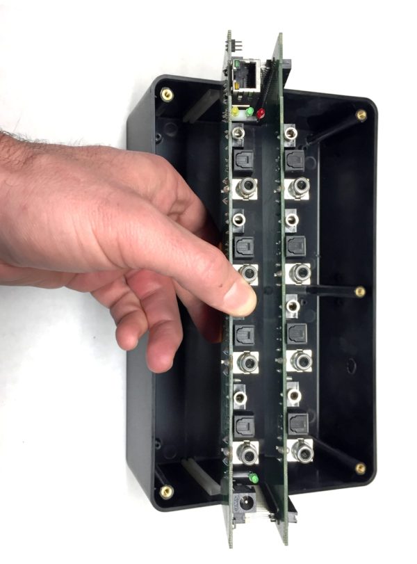 A hand is holding an AudioFetch 4 Channel Add On Card - FETCH4CHADD with a number of wires in it.